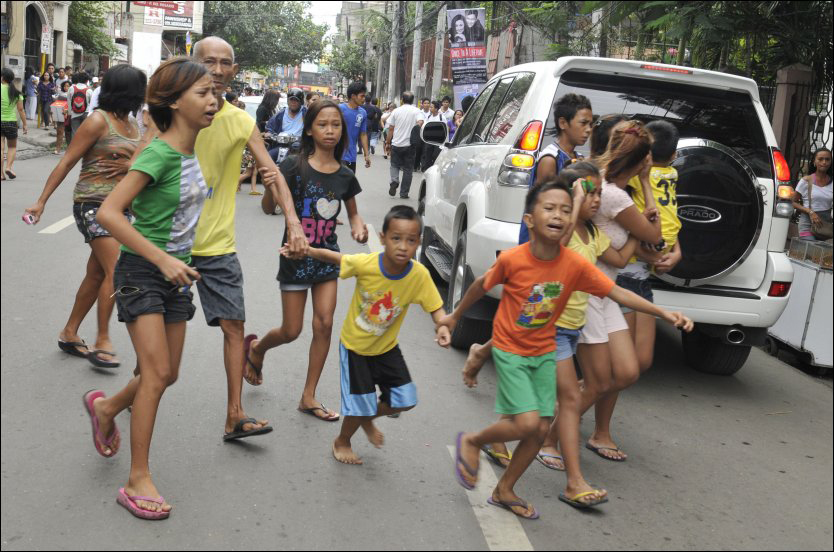 LØPER I SIKKERHET: Flere innbyggere i Ceby City løper bort fra bygninger i byen etter at et jordskjelv rammet landet mandag morgen. Foto: AFP